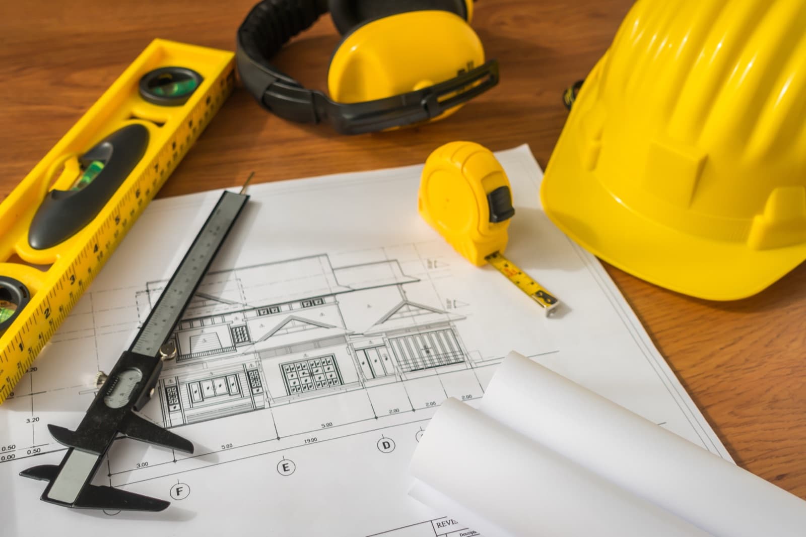 Blueprints, hard hat and tape measure on a workbench